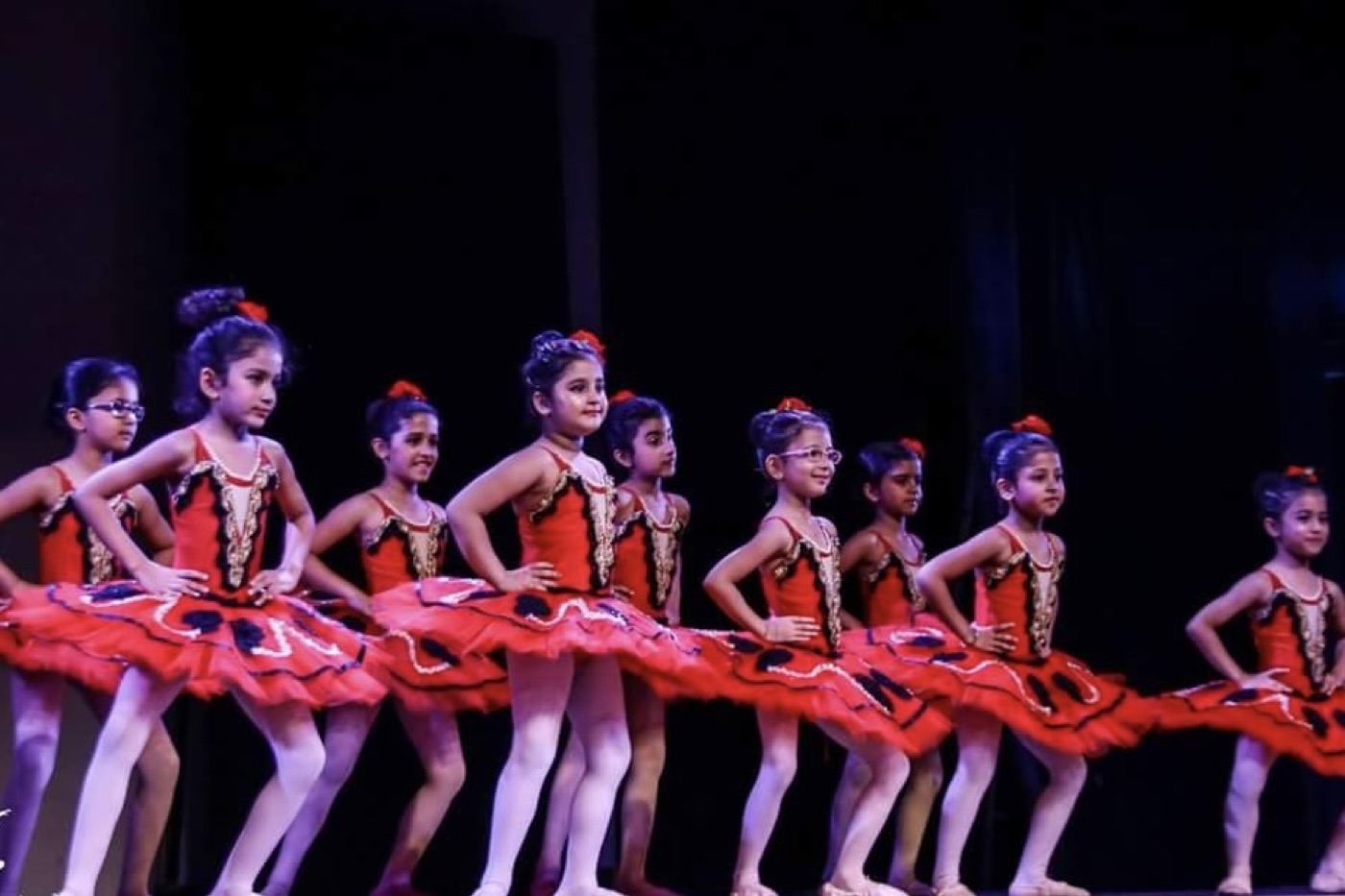 A line of young ballet dancers in red tutus during a performance